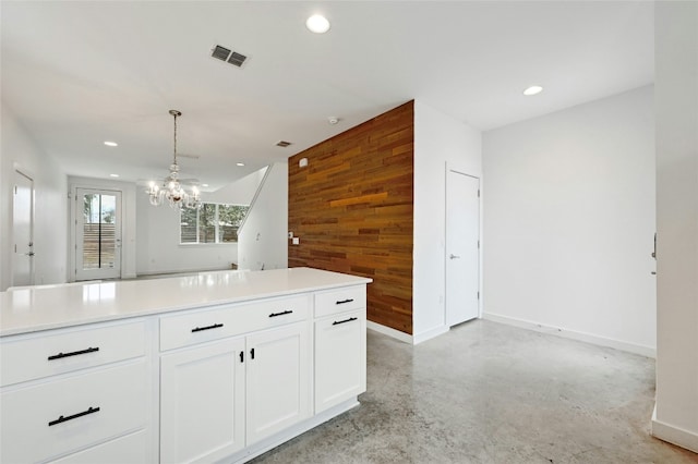 kitchen featuring visible vents, recessed lighting, wooden walls, white cabinets, and concrete flooring