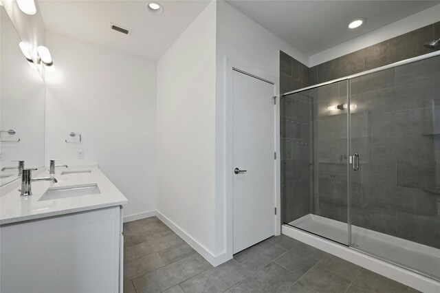 full bathroom featuring visible vents, a shower stall, baseboards, double vanity, and a sink