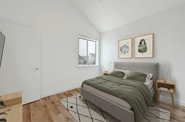 bedroom featuring light wood-style flooring, baseboards, and lofted ceiling