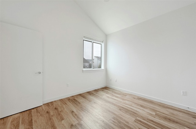 empty room with vaulted ceiling, wood finished floors, and baseboards