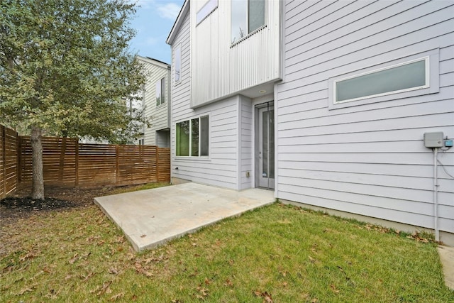 rear view of property featuring a patio, a lawn, and fence