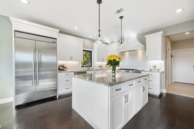 kitchen featuring stainless steel appliances, white cabinetry, hanging light fixtures, and a center island