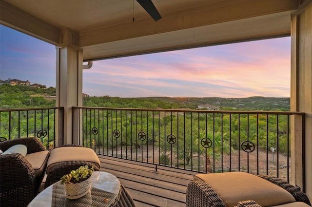 balcony at dusk featuring ceiling fan