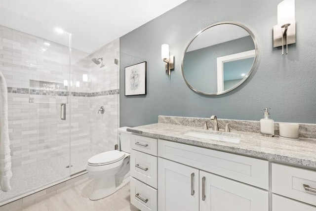 full bathroom with a stall shower, vanity, and toilet