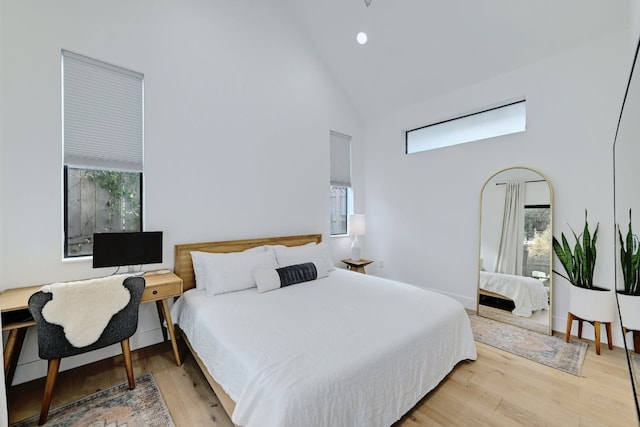 bedroom featuring high vaulted ceiling and light hardwood / wood-style floors