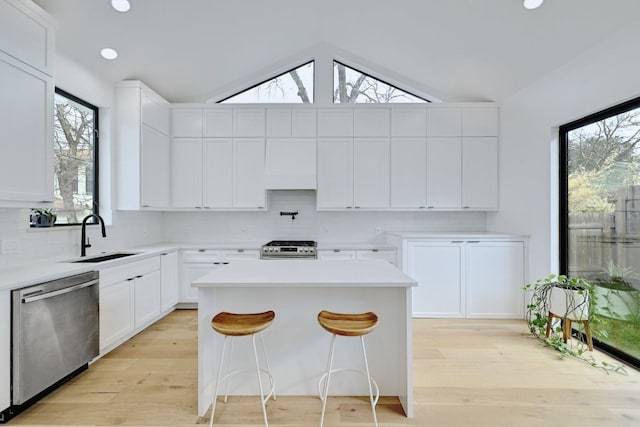 kitchen with sink, a breakfast bar area, white cabinetry, a center island, and stainless steel appliances