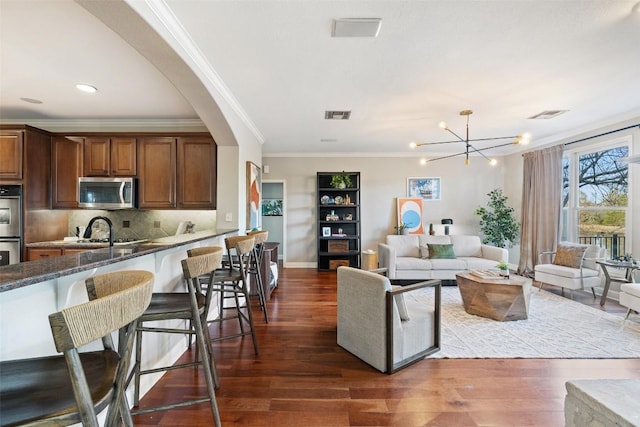 living area with dark wood-style flooring, visible vents, and an inviting chandelier