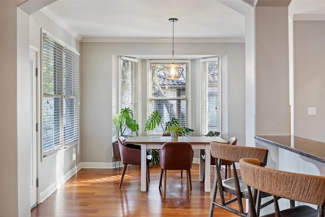 dining room with arched walkways, baseboards, crown molding, and wood finished floors