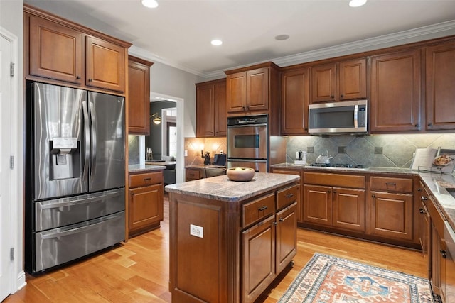 kitchen with stainless steel appliances, light wood-style floors, brown cabinets, and a kitchen island