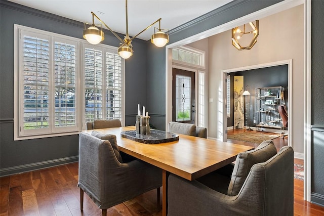 dining room with dark wood-type flooring, ornamental molding, and baseboards