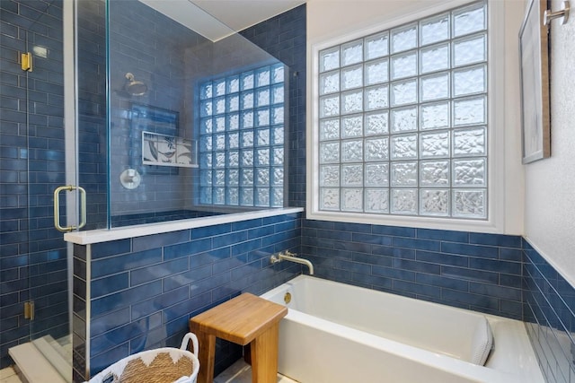 bathroom with a healthy amount of sunlight, a garden tub, tile walls, and a stall shower