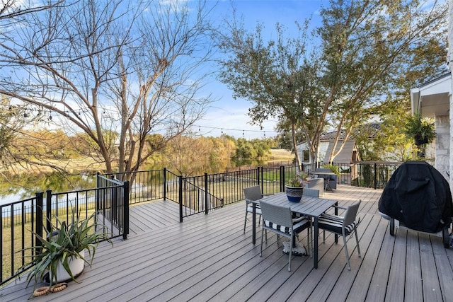 deck featuring a water view, a grill, and outdoor dining space