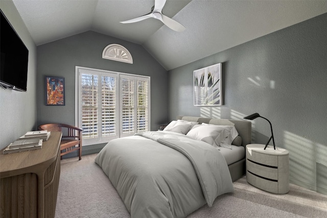 bedroom featuring vaulted ceiling, ceiling fan, a textured wall, and light colored carpet