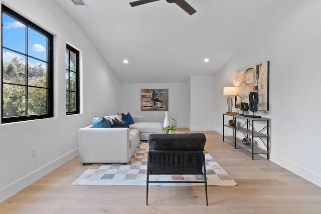 living room with ceiling fan, light hardwood / wood-style floors, and vaulted ceiling