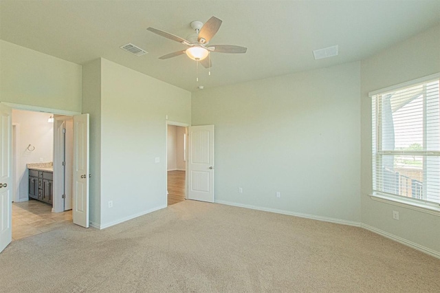 unfurnished bedroom with ceiling fan, light colored carpet, and ensuite bath