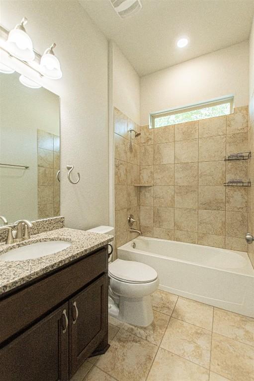 full bathroom featuring tiled shower / bath combo, vanity, tile patterned floors, and toilet