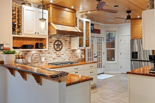 kitchen with butcher block countertops, a breakfast bar, appliances with stainless steel finishes, white cabinets, and kitchen peninsula