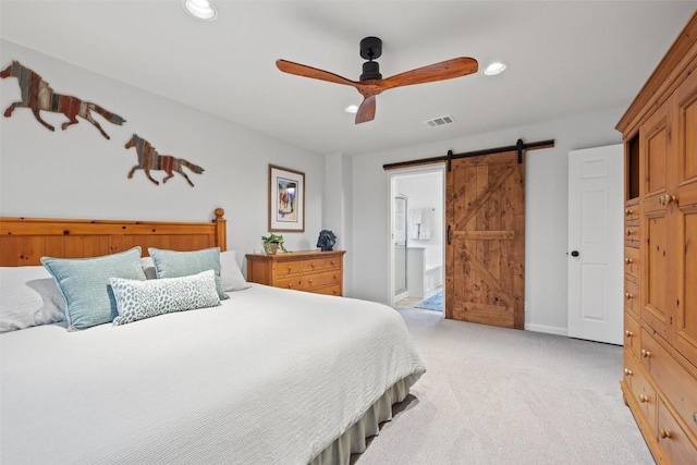 bedroom with light carpet, a barn door, ceiling fan, and ensuite bathroom