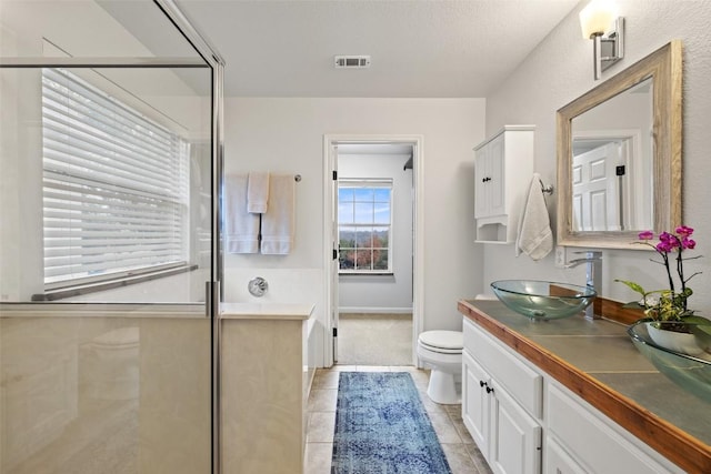 bathroom with tile patterned flooring, vanity, a shower with door, and toilet