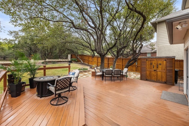 deck with a storage shed and an outdoor fire pit