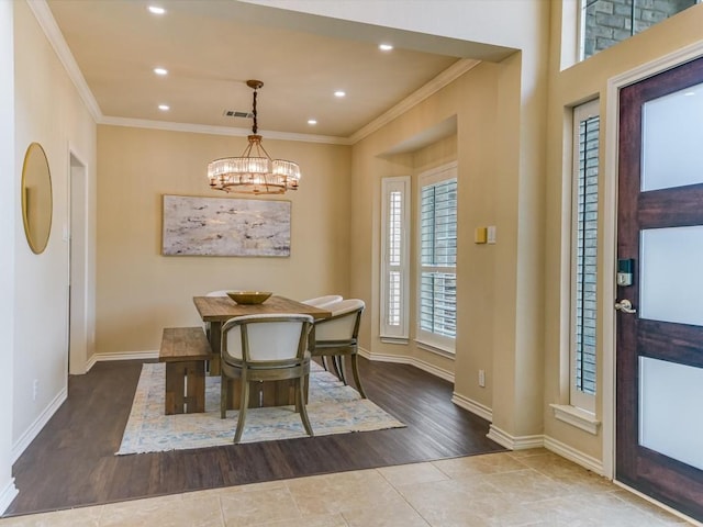 tiled dining room featuring ornamental molding and a chandelier