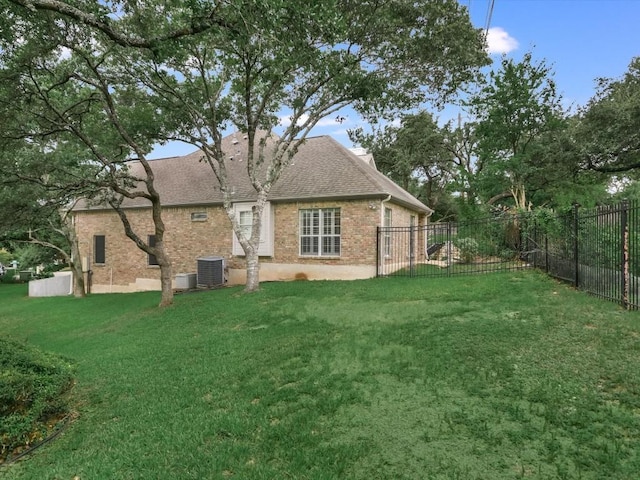 rear view of house featuring central AC unit and a lawn