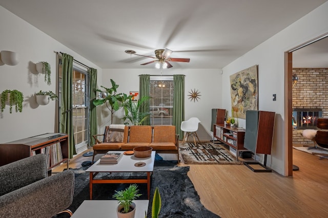 sitting room featuring wood-type flooring, ceiling fan, and a fireplace