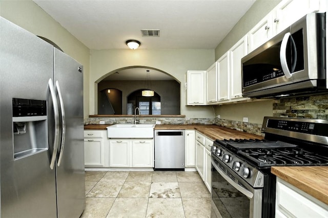 kitchen with white cabinetry, wood counters, appliances with stainless steel finishes, and sink