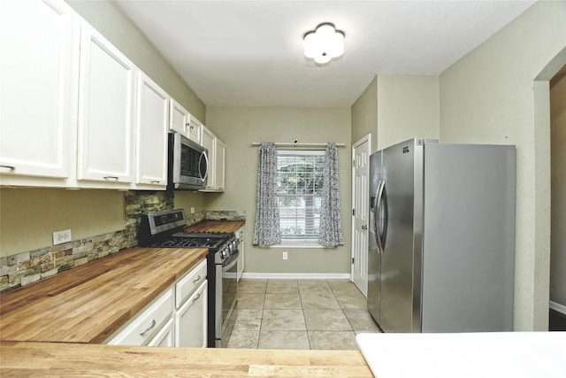 kitchen featuring butcher block counters, light tile patterned floors, white cabinetry, and appliances with stainless steel finishes