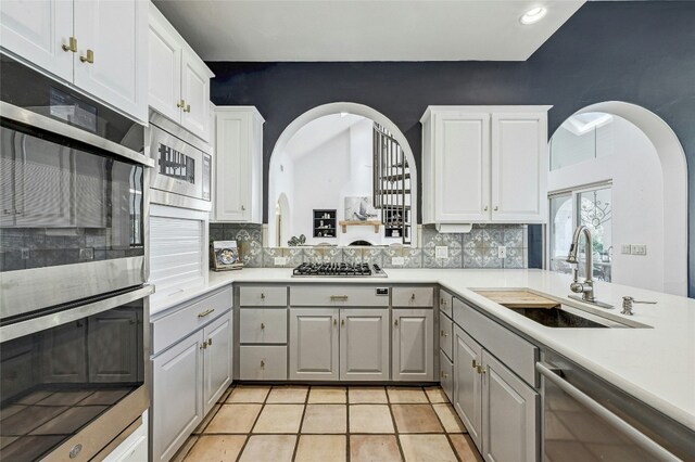 kitchen featuring stainless steel appliances, white cabinetry, sink, and backsplash