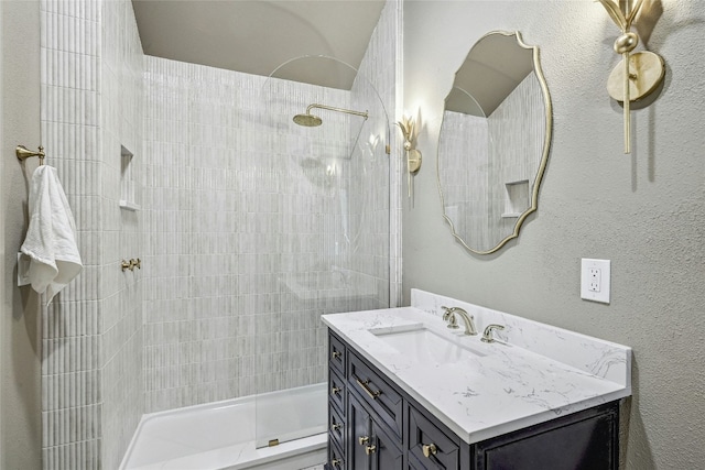 bathroom featuring tiled shower and vanity