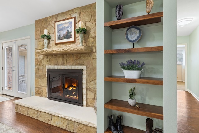 details with hardwood / wood-style flooring, a stone fireplace, and french doors