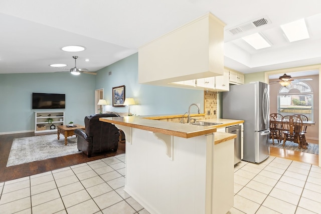 kitchen with light tile patterned flooring, a breakfast bar, sink, kitchen peninsula, and stainless steel appliances