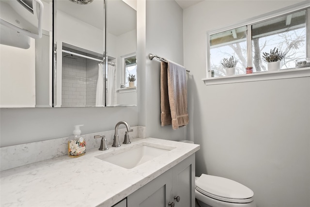 bathroom featuring vanity, toilet, a shower with shower curtain, and a wealth of natural light