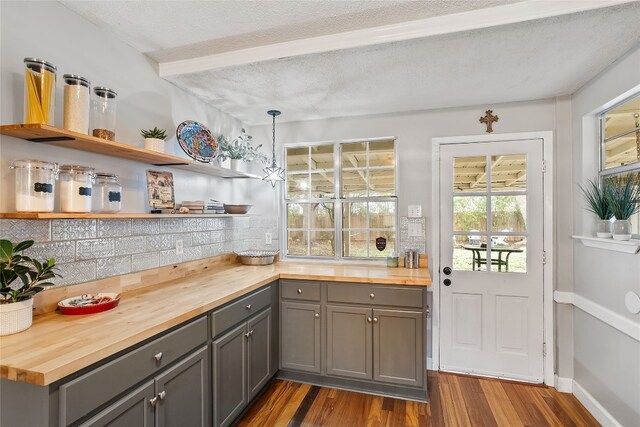 kitchen with butcher block countertops, tasteful backsplash, dark hardwood / wood-style flooring, gray cabinets, and pendant lighting