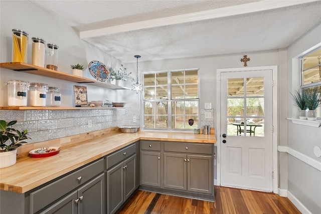 kitchen with dark wood-style flooring, tasteful backsplash, butcher block counters, gray cabinetry, and a textured ceiling