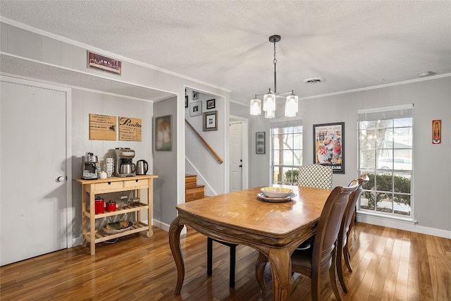 dining space featuring ornamental molding, a chandelier, hardwood / wood-style floors, and a textured ceiling