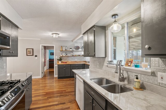 kitchen with sink, dishwasher, pendant lighting, light stone countertops, and decorative backsplash