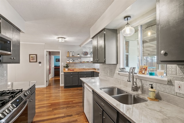 2502 Spruceleaf Cir, Austin, TX 78757 - kitchen featuring a sink, stainless steel appliances, decorative backsplash, wood finished floors, and a textured ceiling