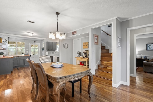 dining room featuring crown molding, an inviting chandelier, hardwood / wood-style floors, and a textured ceiling