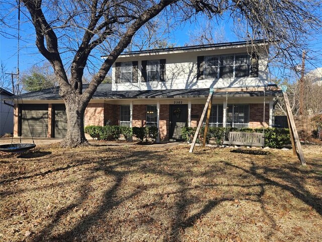 view of front facade featuring a porch, a garage, and a front lawn