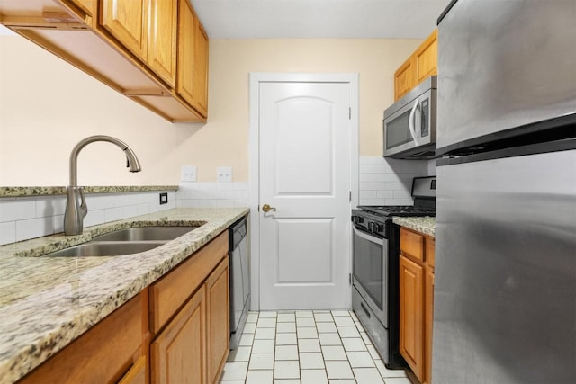 kitchen with sink, decorative backsplash, stainless steel appliances, and light stone countertops