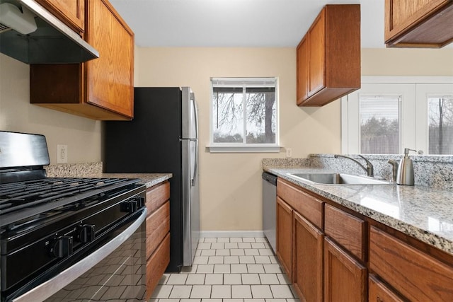 kitchen featuring sink, light stone counters, stainless steel dishwasher, black gas stove, and exhaust hood