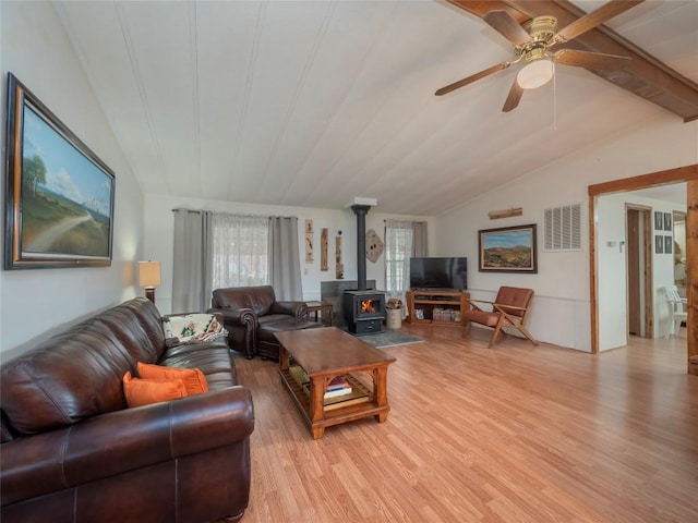 living room with vaulted ceiling, a wood stove, ceiling fan, and light hardwood / wood-style flooring