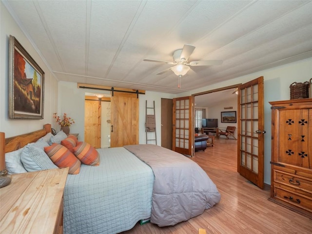 bedroom with french doors, ceiling fan, a barn door, and hardwood / wood-style flooring