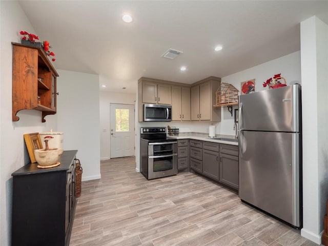 kitchen featuring appliances with stainless steel finishes, sink, gray cabinets, and light hardwood / wood-style floors