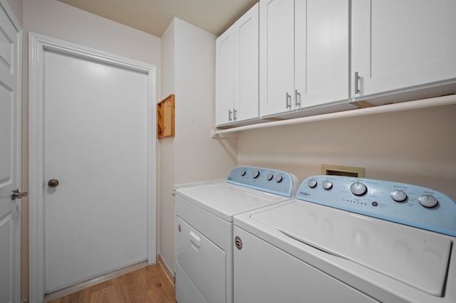 washroom featuring cabinets, washer and dryer, and light hardwood / wood-style flooring