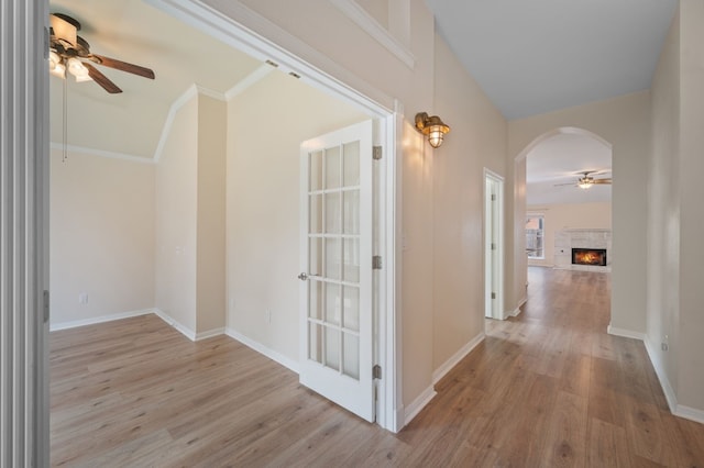 corridor featuring vaulted ceiling, crown molding, and light hardwood / wood-style floors