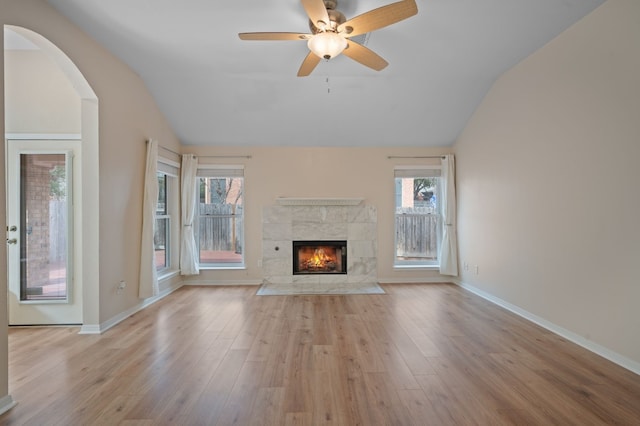 unfurnished living room featuring light hardwood / wood-style flooring, a tiled fireplace, vaulted ceiling, and ceiling fan