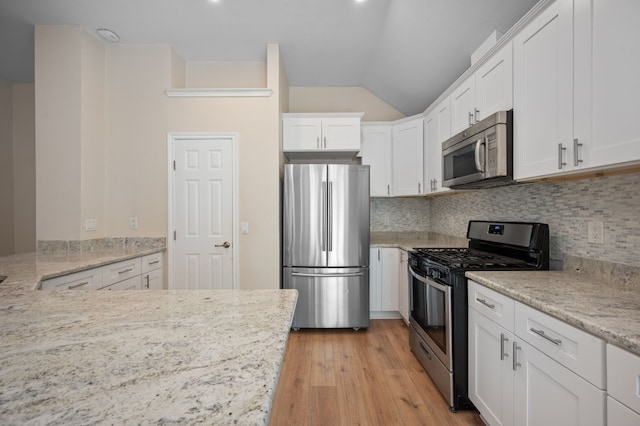 kitchen featuring light hardwood / wood-style flooring, appliances with stainless steel finishes, light stone countertops, decorative backsplash, and white cabinets